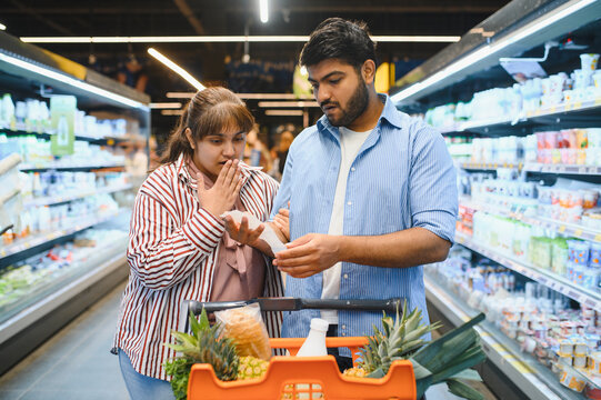 Indian couple checking grocery shopping list in supermarket
