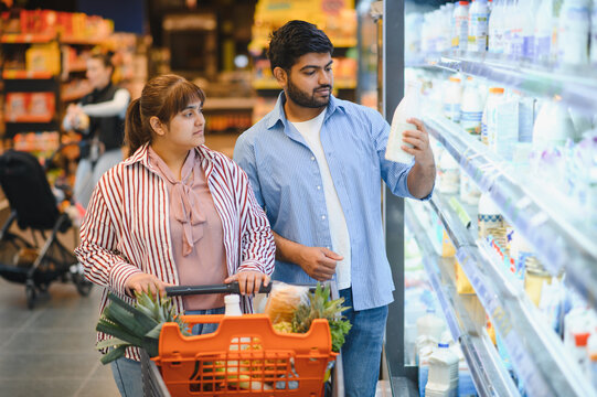 Indian couple choosing milk in grocery store refrigerator