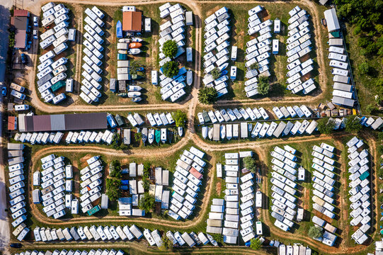 Aerial view of a perfectly aligned caravan park, where rows of white-roofed caravans contrast with the green trees and brown buildings, Rovinj, Istria County, Croatia.