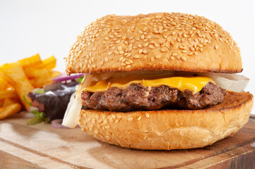Hamburger with potatoes and vegetables on a wooden board