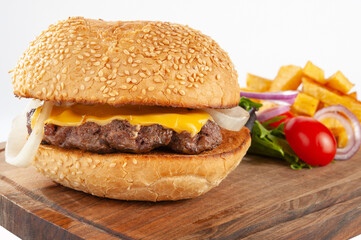 Hamburger with potatoes and vegetables on a wooden board