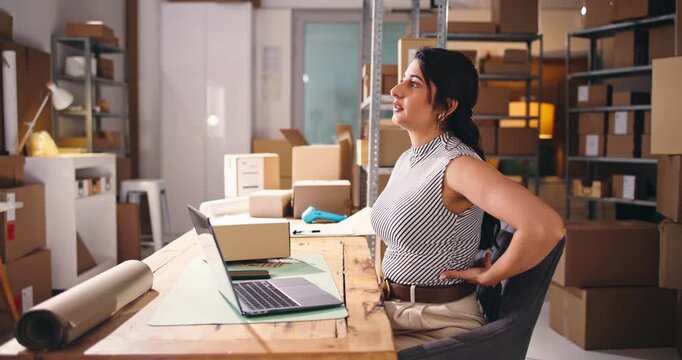 Frustrated, woman and back pain in office with laptop for ecommerce backlog, logistics fail or crisis. Computer, exhausted person and spinal injury with bad posture, supplier issue and courier delay.