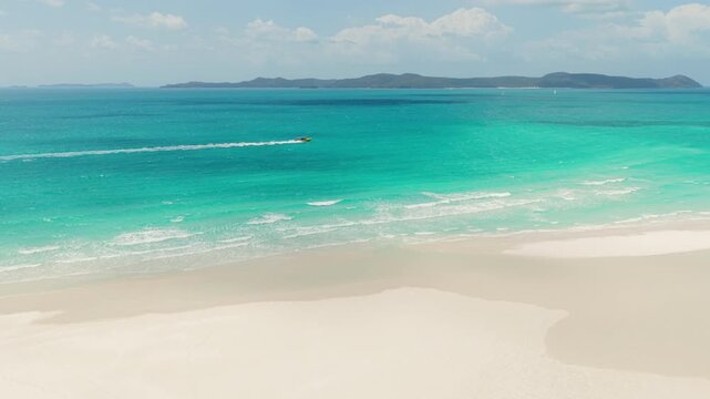 Epic aerial of a boat of tourists and snorkelers by Whitehaven beach in the Whitsunday Islands, Australia, a pristine destination famous for its pure silica sand and crystal-clear turquoise waters.