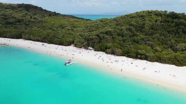Descending aerial of boats, tourists and snorkelers at Whitehaven beach in the Whitsunday Islands, Australia, a pristine landscape famous for its pure silica sand and crystal-clear turquoise waters.