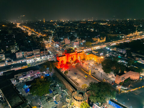 Aerial view of the illuminated New Gate casting a warm glow over bustling streets and vibrant markets at night, Jaipur, Rajasthan, India.
