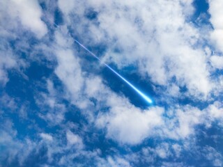 Bolide in the daytime sky. Fireball between the clouds in the sunlight. Meteor trail in the atmosphere. © Nazarii