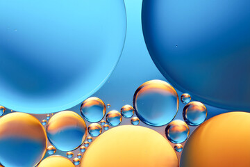 Abstract macro photo of liquid bubbles against a blue background with warm yellow 
