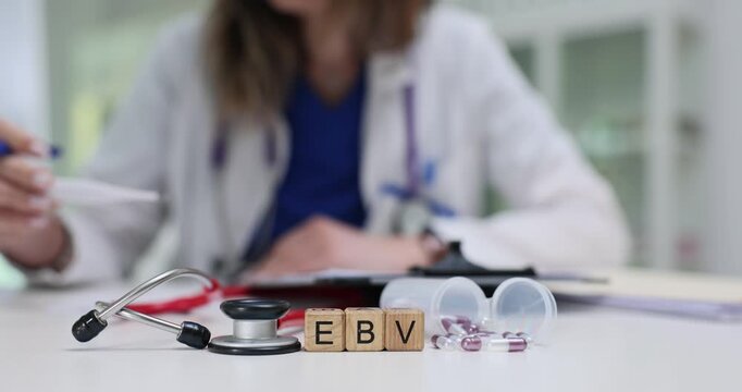 Wooden cubes spell abbreviation EBV by scattered capsules. Woman doctor writes record about Epstein Barr virus infection case for patient in hospital