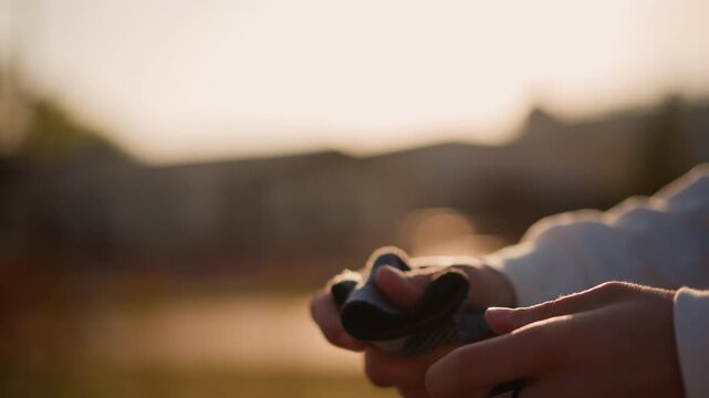 sunset hands adjusting fingerless glove, closeup of guitarist warming fingers before performance in park, warm golden light, textured fabric wrap and ring, soft bokeh background conveying calm