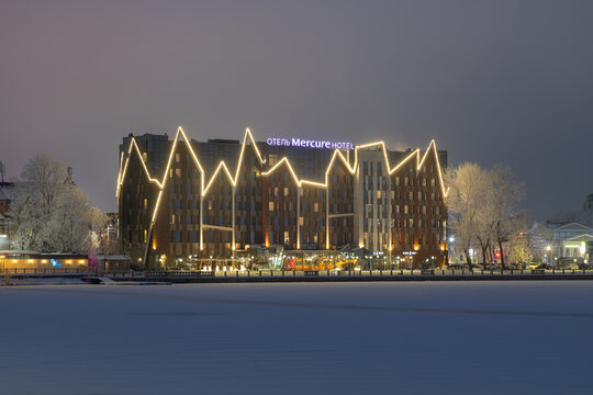 Winter evening view of the glowing Mercure Hotel from a frozen lake