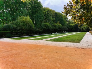 Obraz premium Sidewalk in public park. Wet benches and street lamps along the avenue in the park. Petite clture et panneau dindication. Red rubber recreational jogging path in city. The morning activity.
