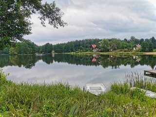 Fishing boat on idyllic shore. Boat on the river.  . View of a beautiful lake in a pine forest at summer. The water is covered with green slime. Magnificent lake view in the forest.