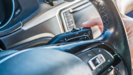Close up driver hand using windshield wiper lever inside vehicle