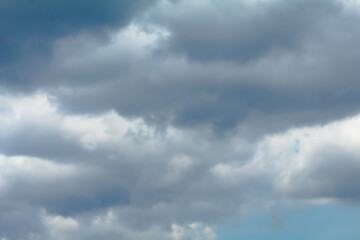 Obraz premium The sky is filled with white clouds, creating a moody atmosphere. The clouds are scattered throughout the sky, with some appearing closer to the ground and others higher up.