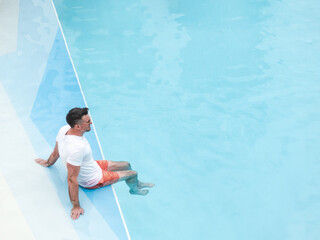 Handsome man relaxing by pool on luxury cruise ship deck. Floating hotel concept, all-inclusive vacation and premium travel. Top view. Perfect for holiday and travel themes © Svetlana