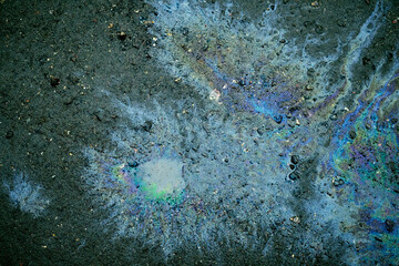 Oil slick creating abstract iridescent rainbow colors on asphalt.