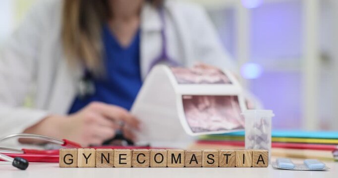 Wooden cubes spell word Gynecomastia near chest tissue images. Doctor shows breast cross section scan writing treatment plan for hormone imbalance