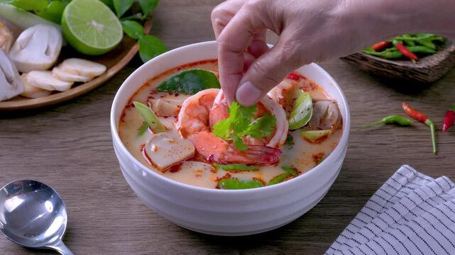 Prawn Tom Yum in a white bowl on a wooden table
