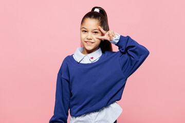 Little kid girl 8-9 years old wears blue shirt have fun cover eye showing victory sign isolated on...