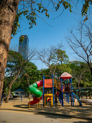Colorful children playground equipment with spiral slide tunnel and climbing structure in urban park surrounded by trees