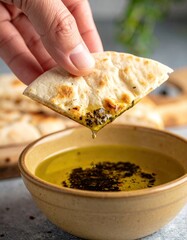 Close Up Of A Hand Dipping Flatbread Into A Bowl Of Olive Oil And Herbs With A Shallow Depth Of Field