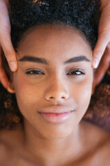 Naklejka premium Vertical close up of young woman looking at camera during facial massage in spa