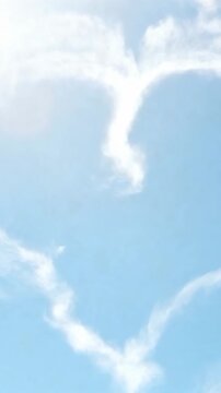 Vertical video: Nudging heart cloud curling then fraying into wisps under sun halo by high winds