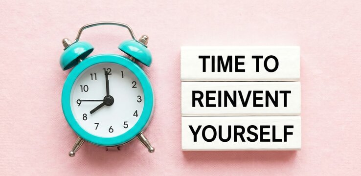 TIME TO REINVENT YOURSELF text on coloured blocks next to blue alarm clock. Concept for personal growth ,work, success, time
