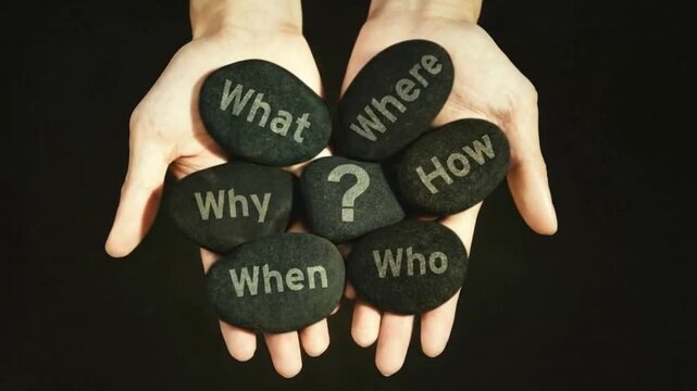 Hands holding stones engraved with 5W1H questions and question mark