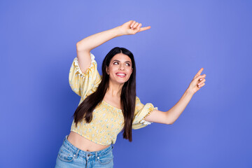 Young woman dances against blue background in yellow blouse jeans lifestyle glamour fashion pose