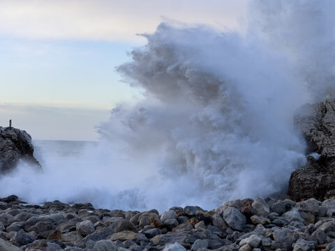 Powerful ocean wave impact with dense sea foam on rocky Atlantic coastline creating dynamic natural energy