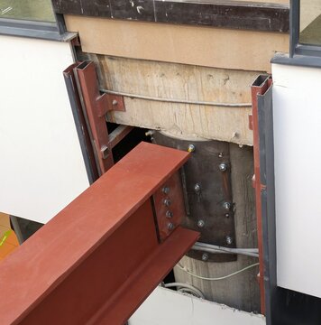 Primer plano de viga de soporte de metal con pernos sujetada en muro de edificio para su rehabilitaci&oacute;n 