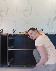 DIY kitchen cabinet assembly square photo, woman assembling modern kitchen furniture during home renovation, copy space