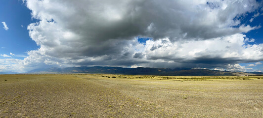 Steppe against the background of the Altai mountains on a beautiful cloudy day. Panoramic view.