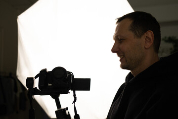 The silhouette of a cameraman in front of a big light on a dark studio background. symbolizing filmmaking, video production and creative media.