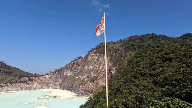 Cinematic 4K View of the Indonesian National Flag Blowing in the Wind Above Kawah Putih Crater at the Cantigi Skywalk in Ciwidey West Java, Indonesia