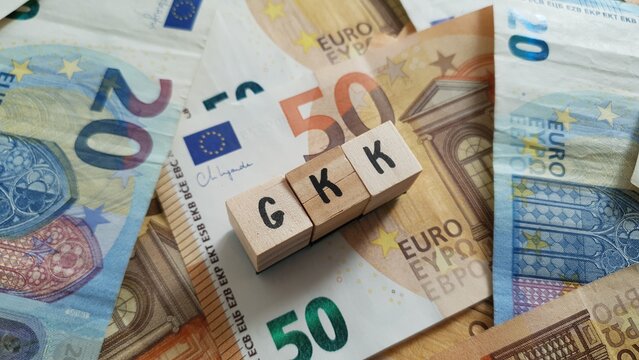 GKK acronym made of wooden letter cubes on pile of Euro banknotes. Geb&auml;ude-Kostenversicherung (Building Cost Insurance)
