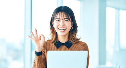 PCの前で笑顔でOKサインを出す女性