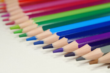 Fototapeta premium New wooden colored pencils of rainbow colors, perfectly sharpened, lie on table