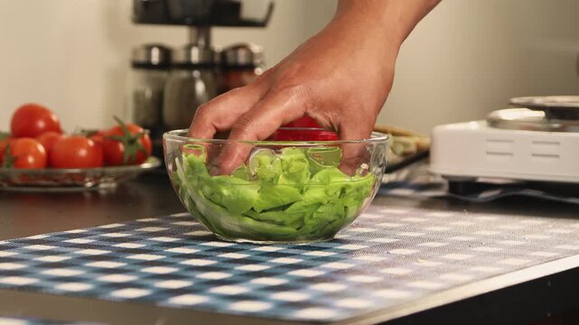 Close up of a hand removing lettuce from water and letting it drain, showing vegetable washing process, freshness, and healthy kitchen preparation routine.