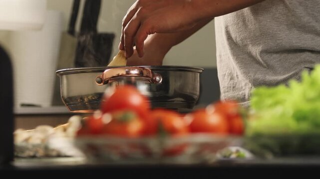 Close up of chef hands stirring a stew with a wooden spoon in a pot, showing cooking process, homemade meal preparation, and warm kitchen routine.