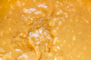 Smooth peanut butter with glossy swirls and small nut pieces, conveying indulgent flavor and homemade simplicity. The abstract food texture works well for nutrition, breakfast, and cooking concepts.