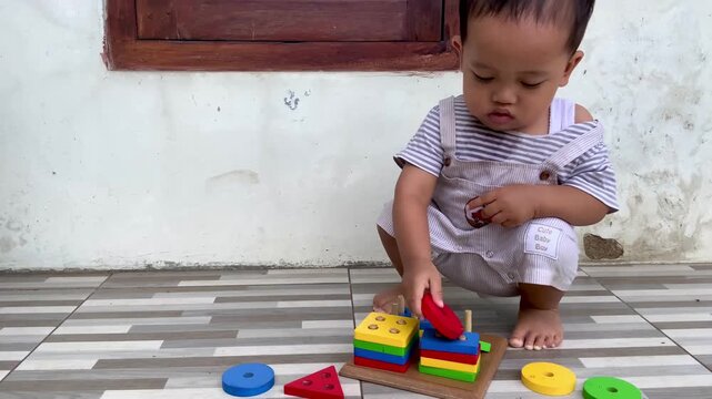 Asian Toddler Playing with Montessori Wooden Geometric Shape Sorter