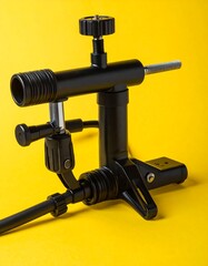 Black metal mechanism with tubes, knobs, and stand on yellow