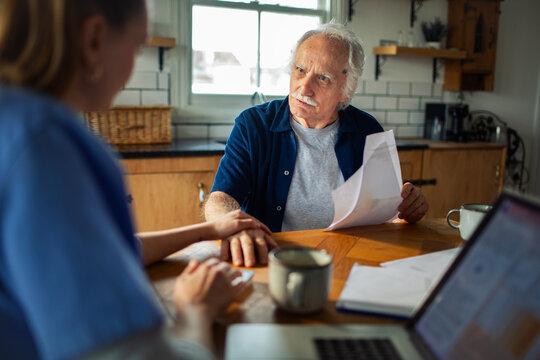 Senior man consulting with caregiver at home kitchen