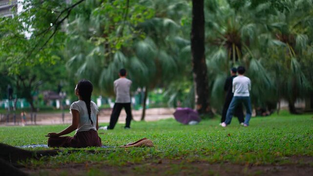asian people practice meditation and qi gong in green city park, woman meditating in nature while people practice qigong, mental health and mindfulness concept 4k