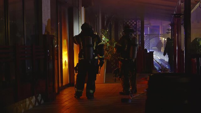 fire brigade extinguishes a burning building at night