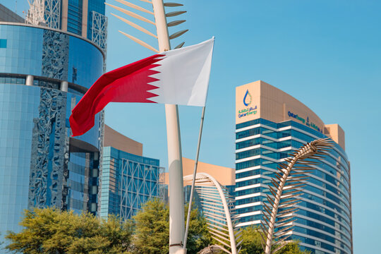 1 December 2025, Doha, Qatar: Qatari flag representing national identity, proudly flying above modern glass buildings in the thriving city