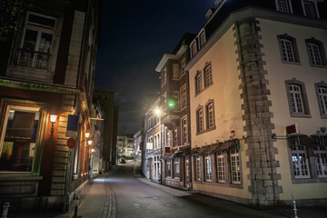 Fototapeta premium Mostardstrasse street in Aachen, Germany at night, empty and quiet in the old town, with historic buildings, street lamps and an atmospheric urban nightscape.