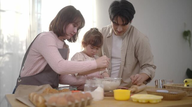 Family baking together at home making cookies with a child in the kitchen